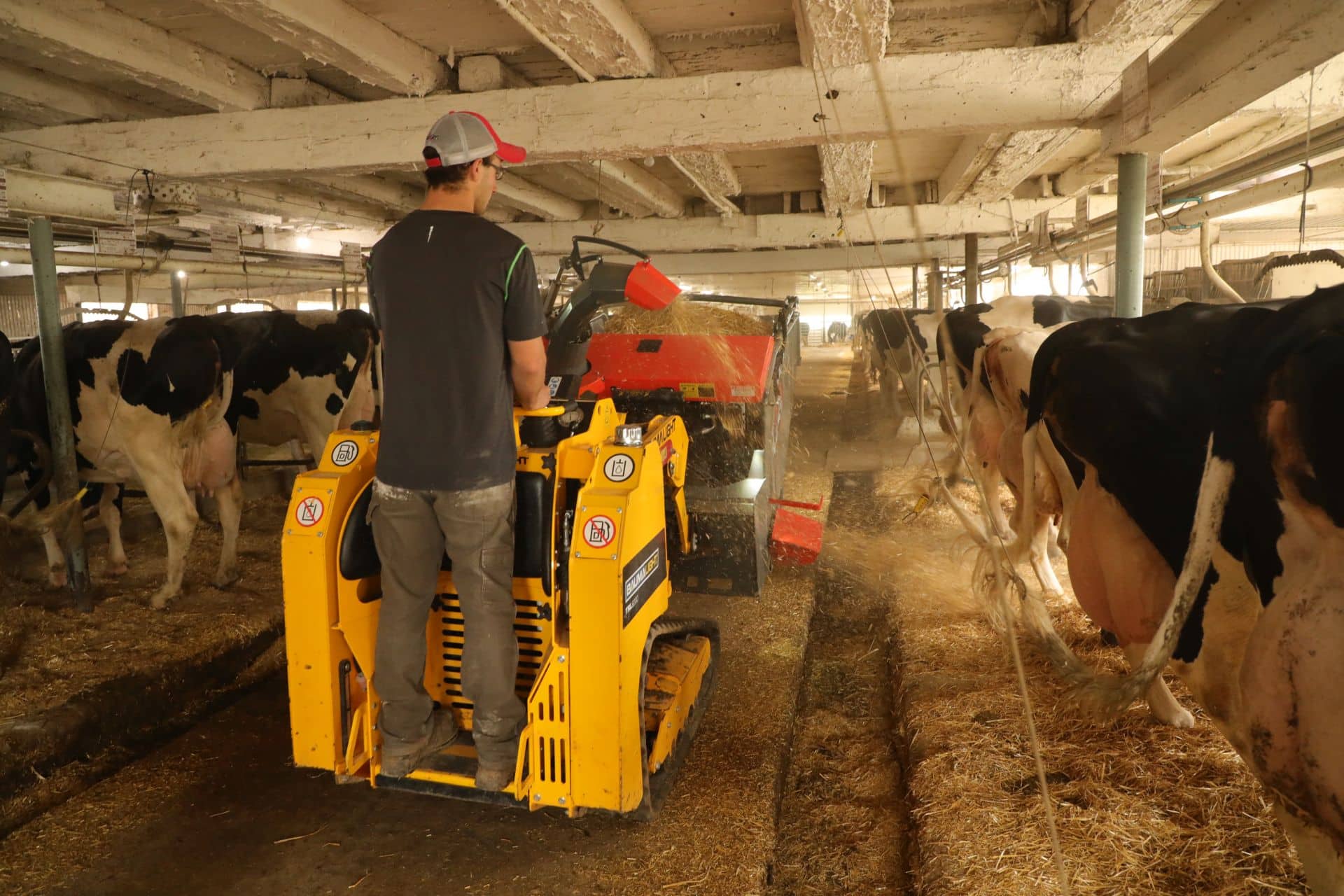 a mini skid steer with a farmer on it is blowing straw with the attached straw processor